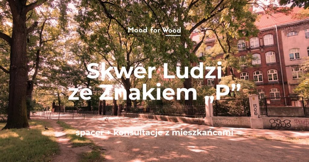 Parkowy skwer z dużymi drzewami przy ulicy, z tyłu widać ceglasty budynek z wieloma oknami. Tekst na środku zdjęcia: Mood for Wood Skwer Ludzi ze Znakiem „P” Na dole napis: spacer + konsultacje z mieszkańcami